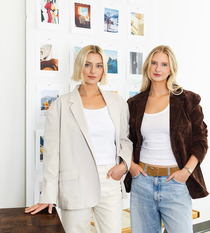 Two women in blazers standing in front of a wall of prints