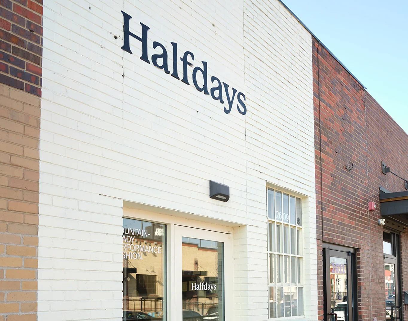 Halfdays storefront with the wordmark on a white brick wall