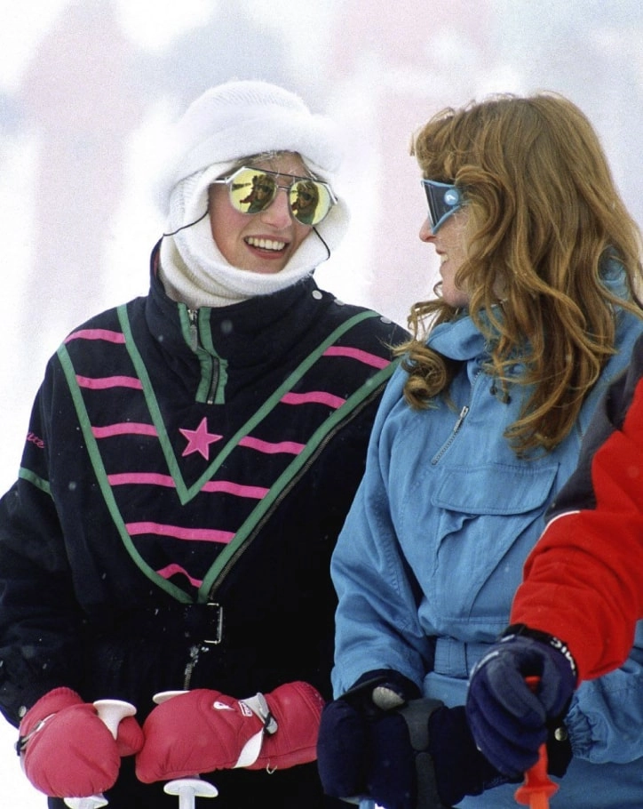 Two friends in matching retro ski jackets with pink and green stripes