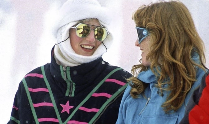 Close view of two skiers laughing in striped jackets and goggles