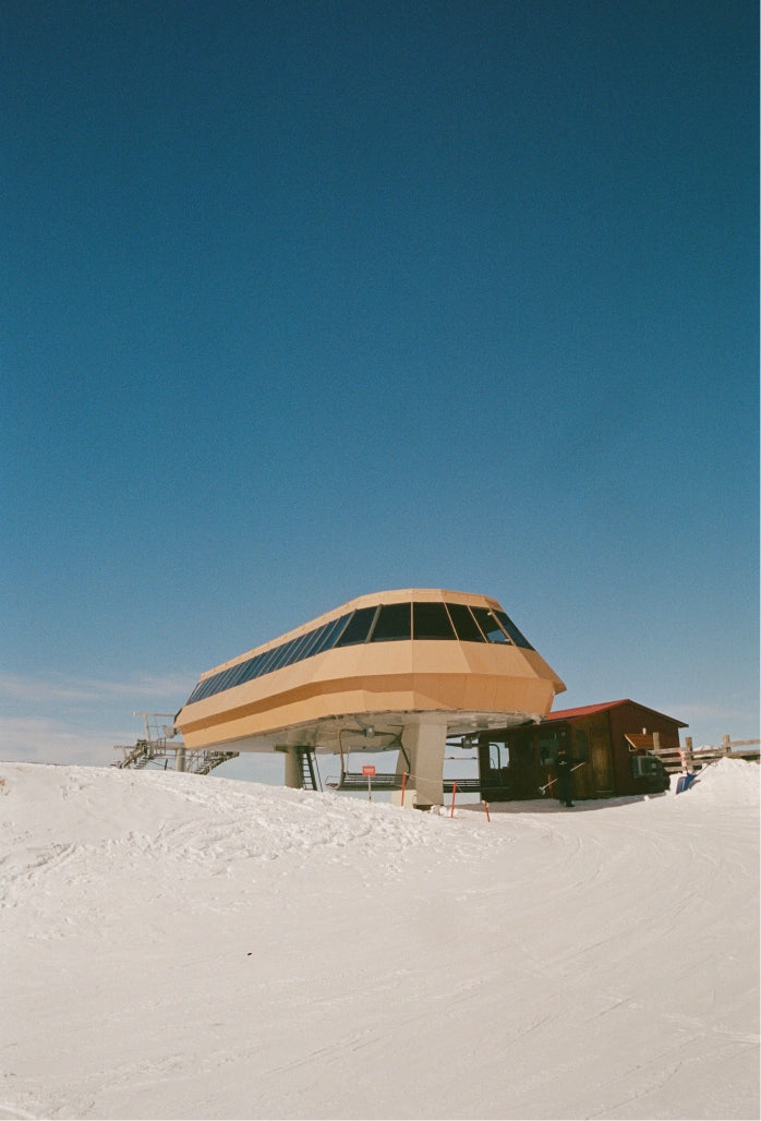 Chairlift station on a snowy hill under a blue sky