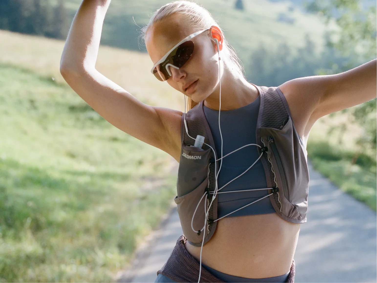 Woman raising her arms in a hydration vest on a hillside