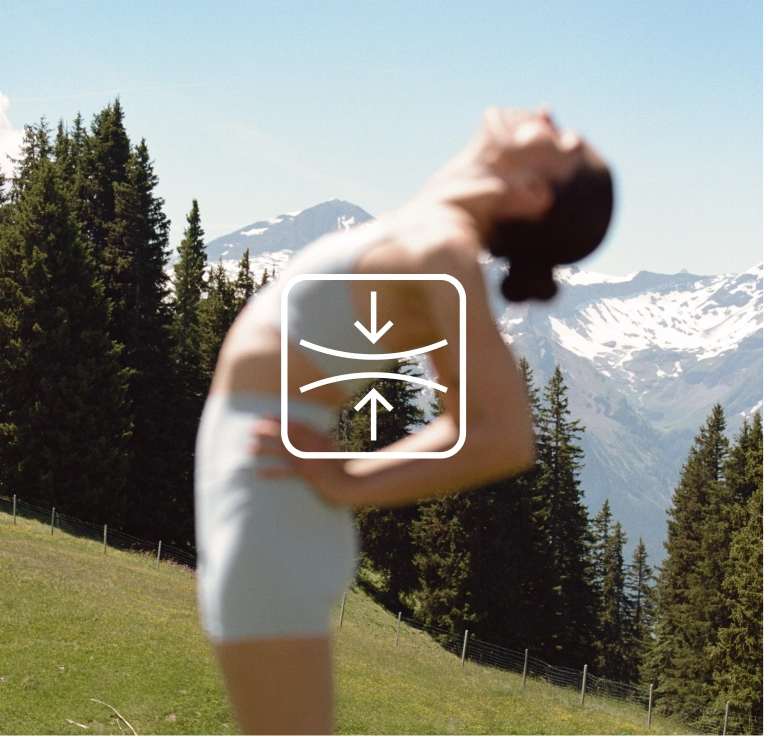 Woman bending back in light shorts with snowy peaks behind her