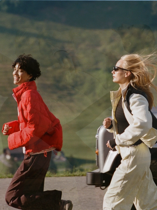 Two runners in a red puffer and a beige jacket on a trail